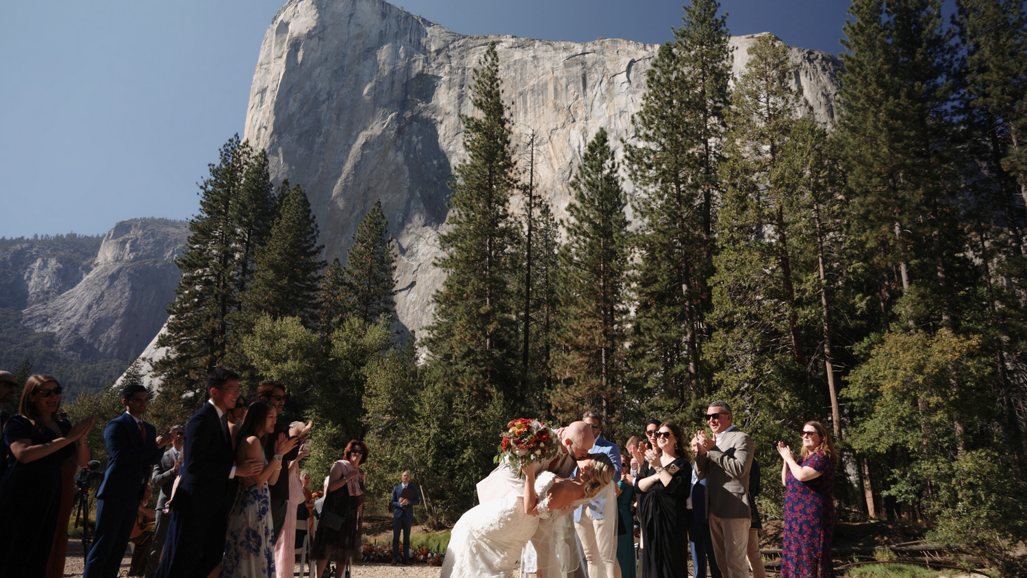Wedding ceremony setup with wooden chairs facing majestic granite cliffs of Yosemite Valley on a sunny day.
