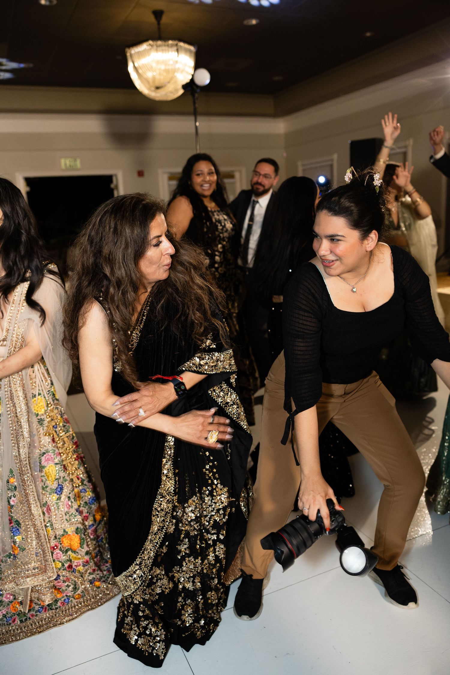 Wedding reception dance floor filled with guests dancing and celebrating in black and sparkly attire.