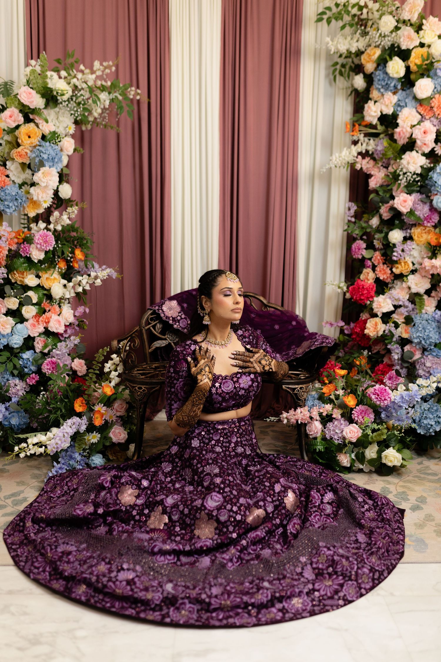 Purple sequined gown with floral backdrop creates an elegant scene with romantic lighting and decor.
