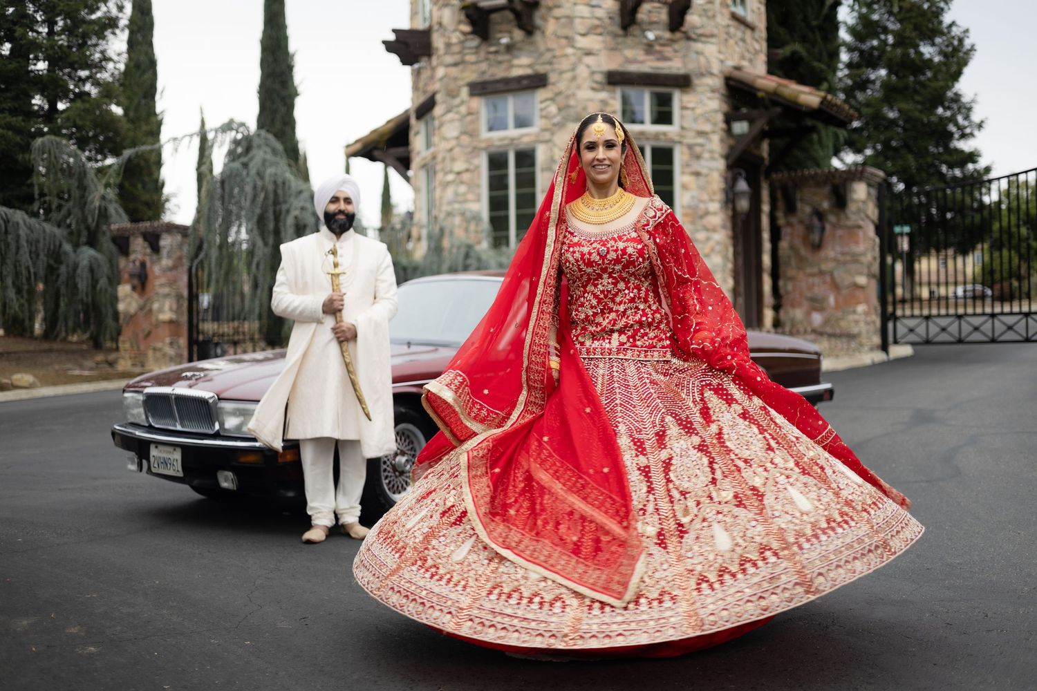 Stone building backdrop frames elegant wedding portraits with traditional South Asian formal wear.