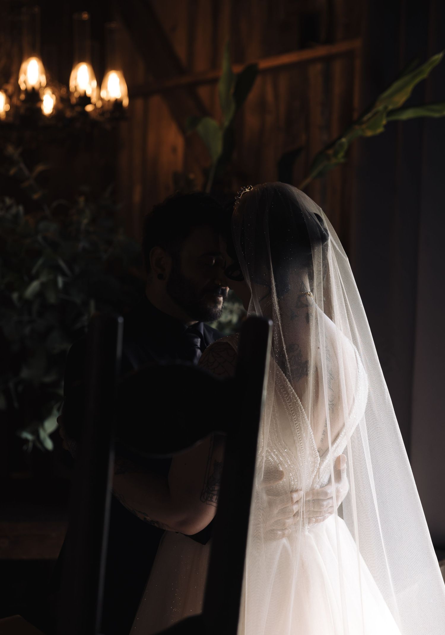 Atmospheric back view of a bride in a flowing veil with warm lighting.