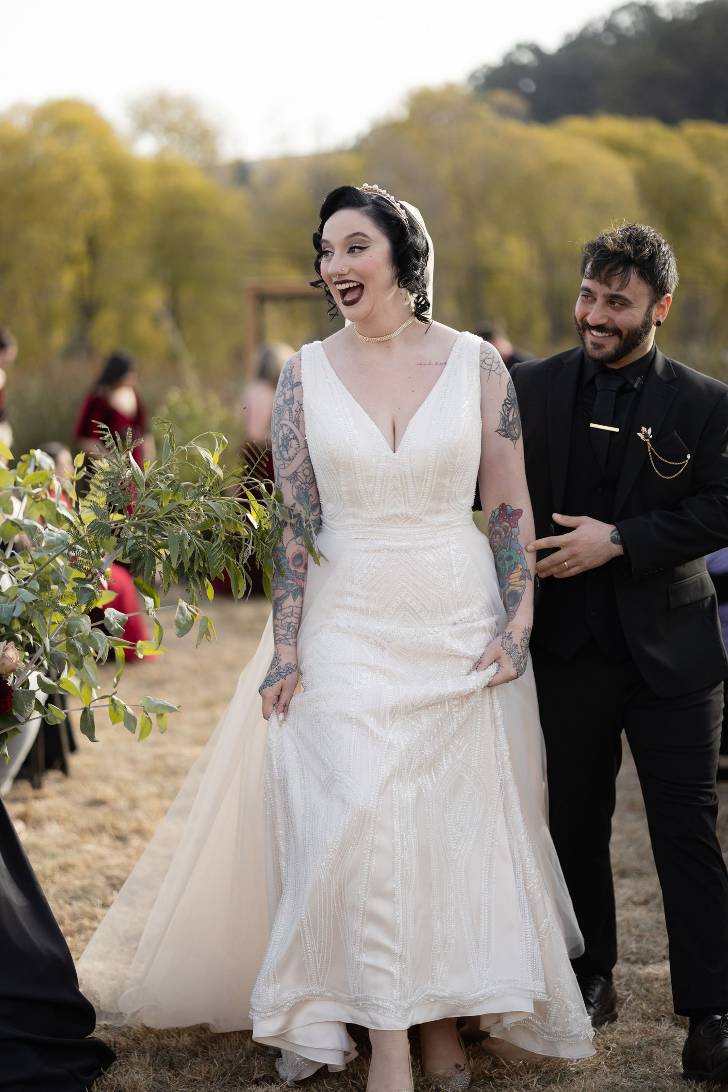 Wedding party in white dress and black attire walking through an autumn field.