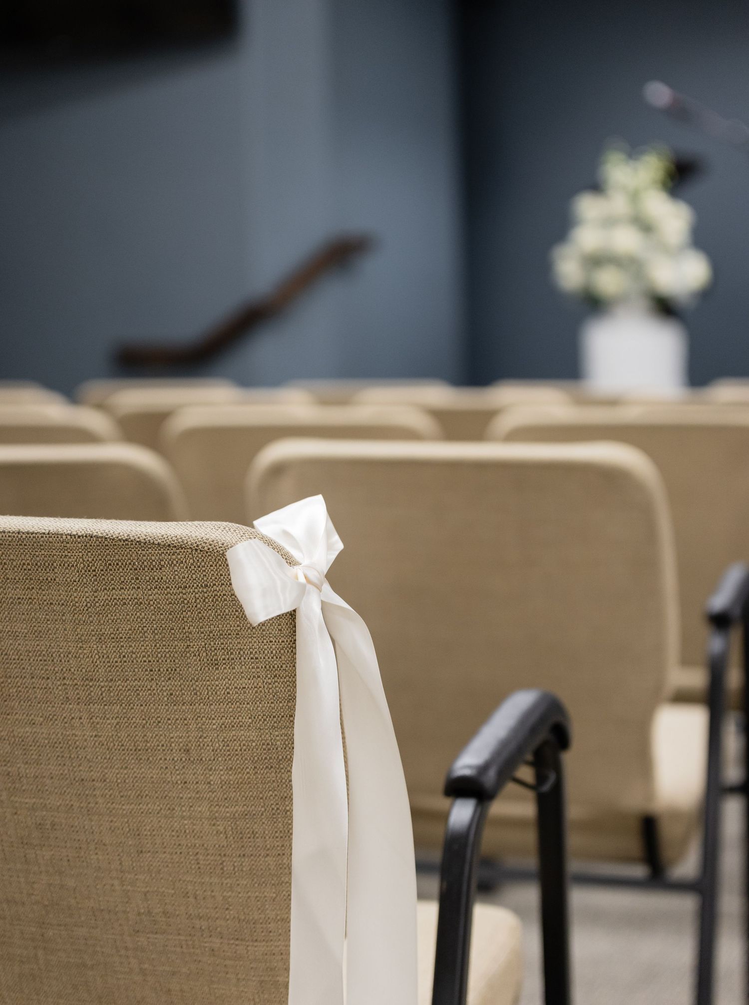 White satin bows tied elegantly on the backs of brown chairs for a formal event.