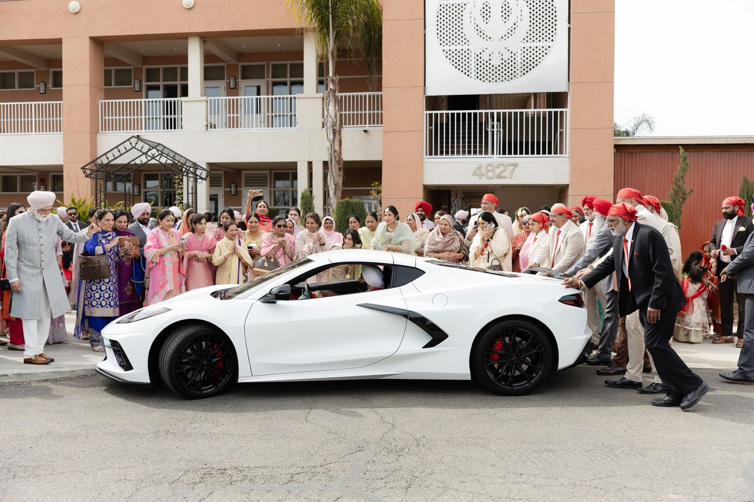 A white stretch limousine parked outside a building with a crowd of people gathered nearby.