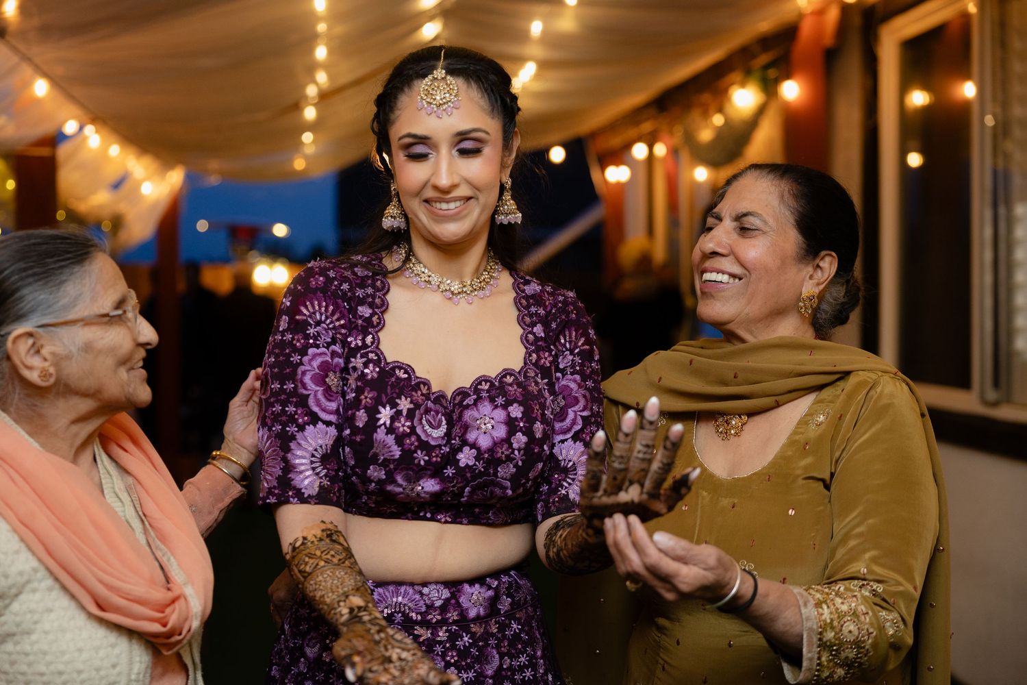 Wedding guests celebrate and dance together under warm string lights during an evening reception celebration.