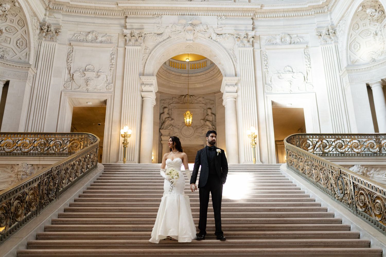 Elegant white marble staircase with ornate gold railings in a grand baroque palace interior.