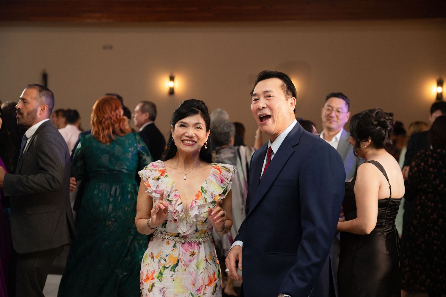 Couple in formal attire smile and laugh together at wedding reception celebration.