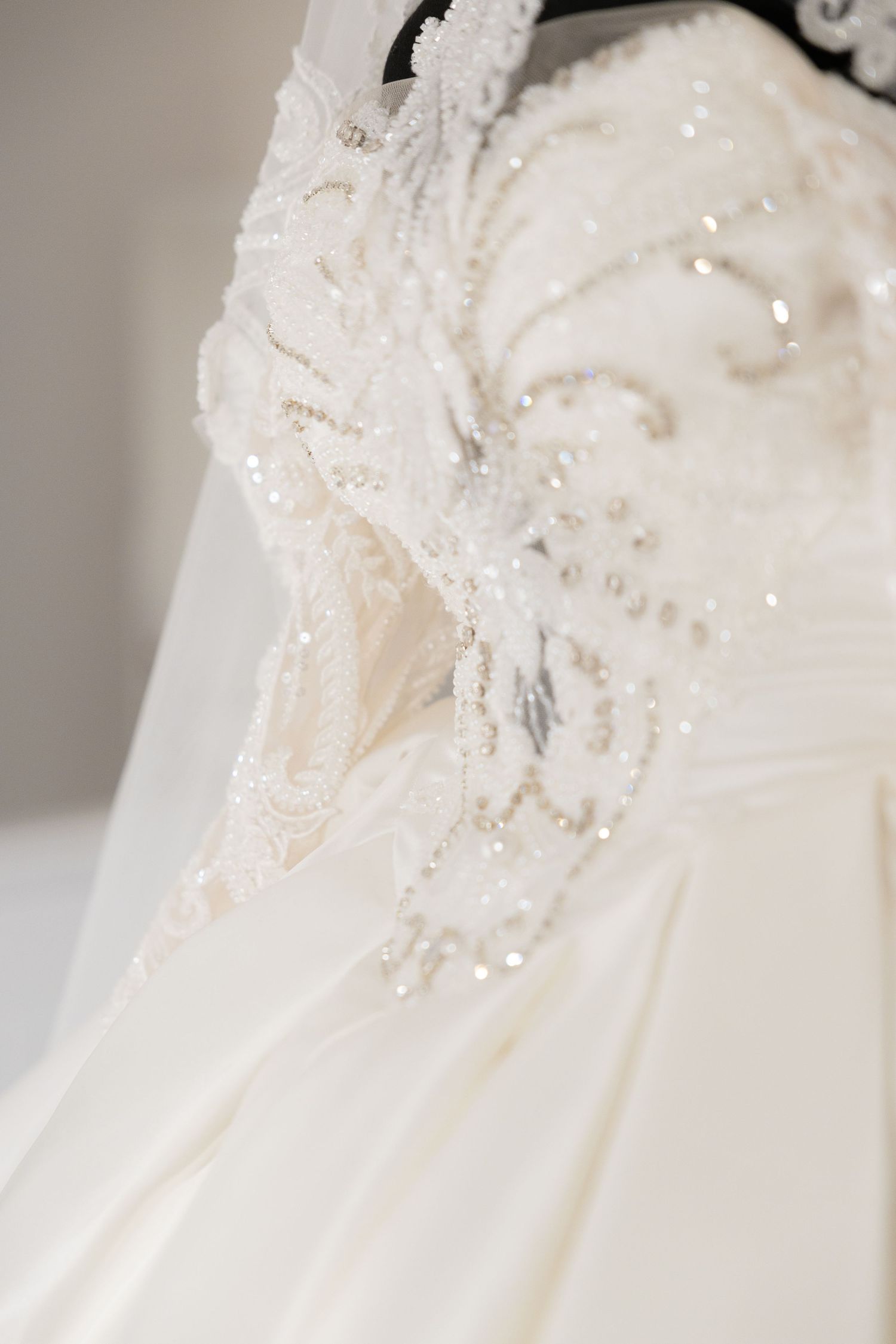 Close-up of intricate beadwork and lace details on a white wedding gown.