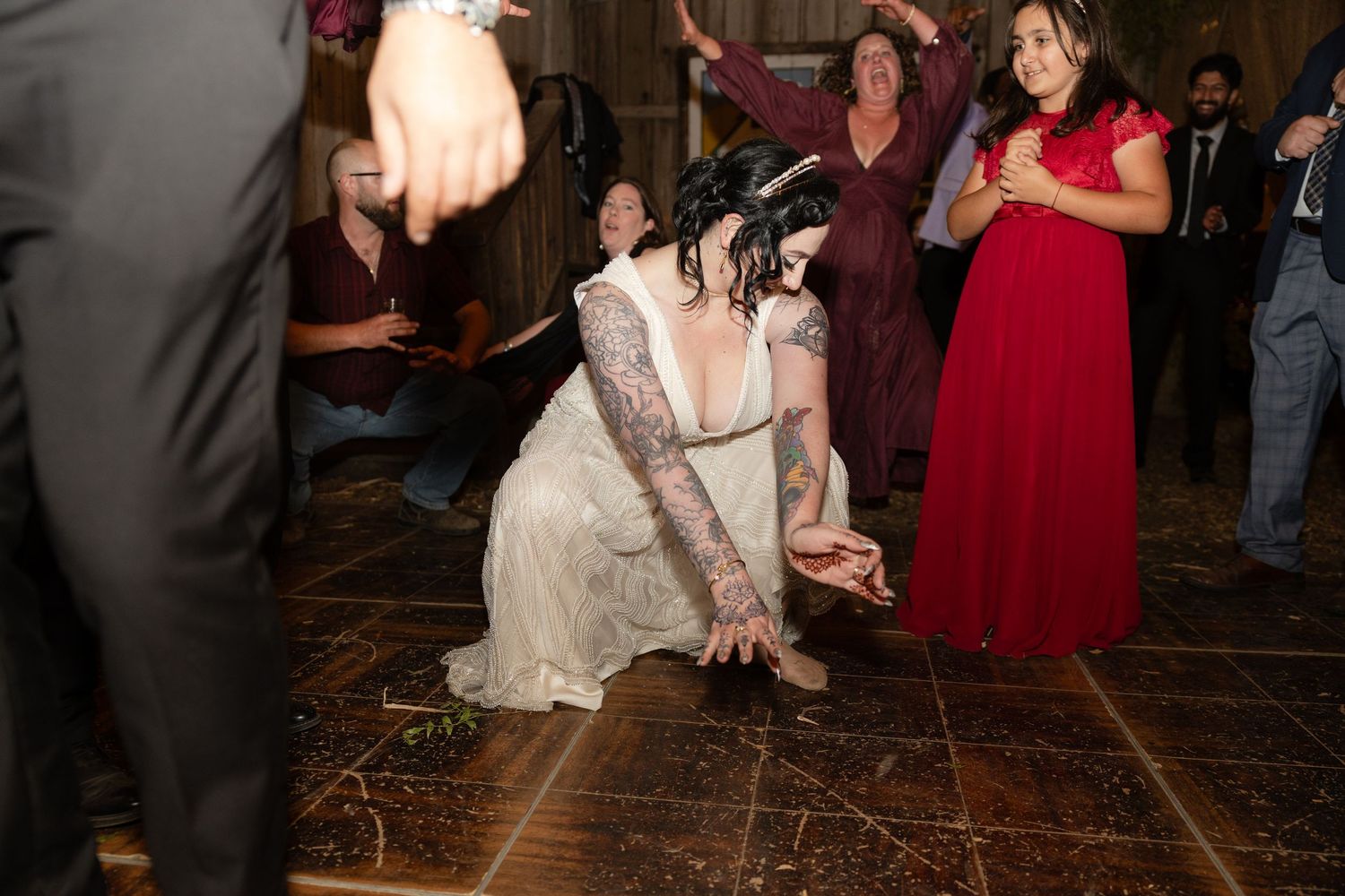 Wedding celebration in a rustic venue with guests dancing and burgundy bridesmaid dresses.