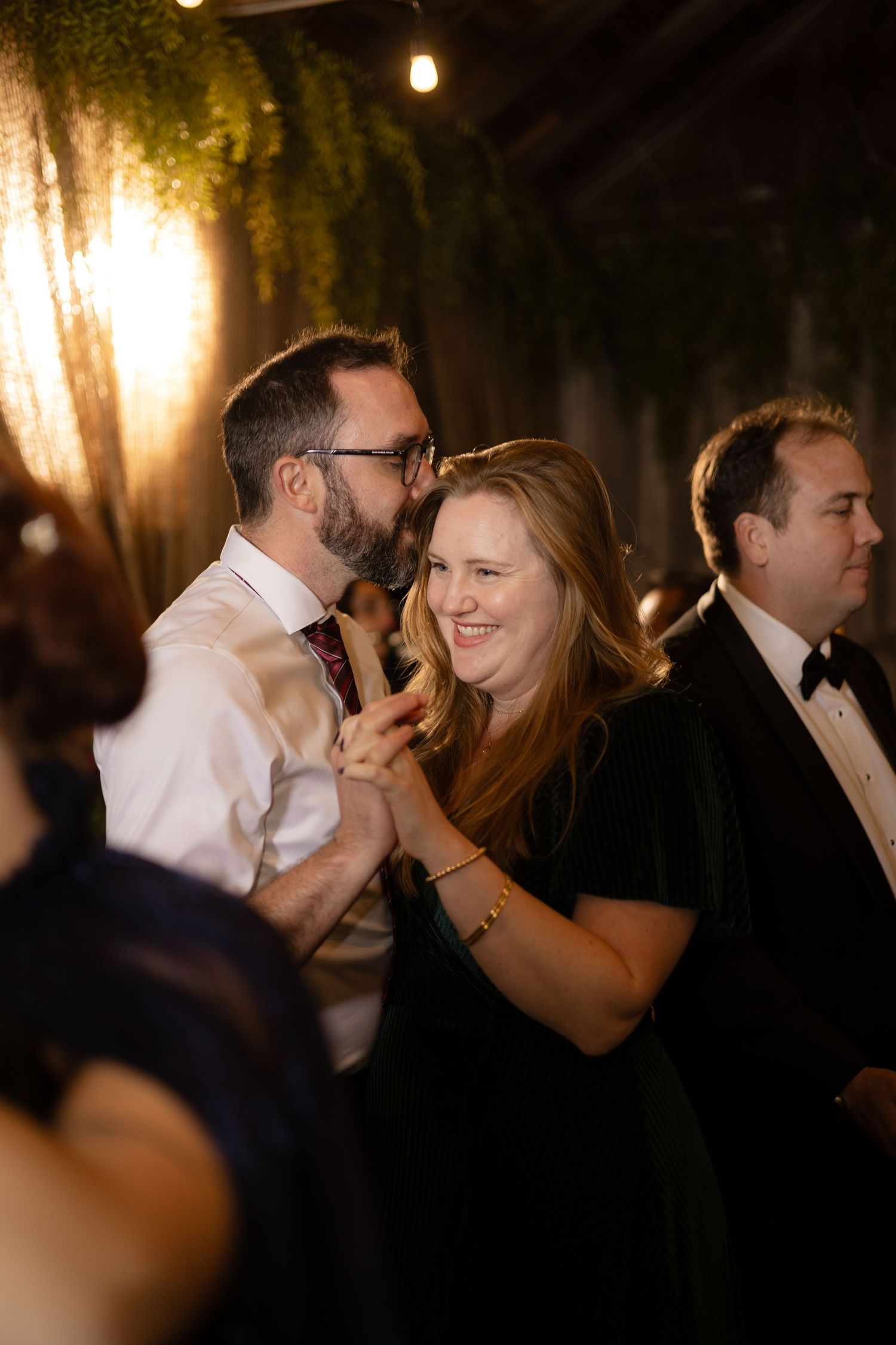 Wedding reception dance floor filled with couples dancing under warm lighting.