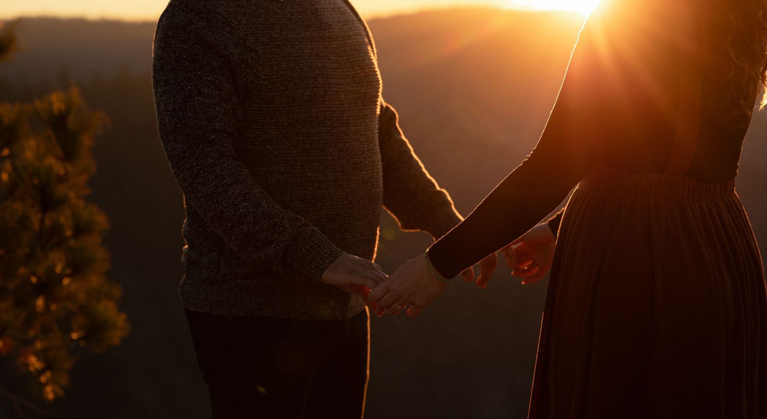 Two silhouettes share an intimate moment against a warm sunset backdrop.