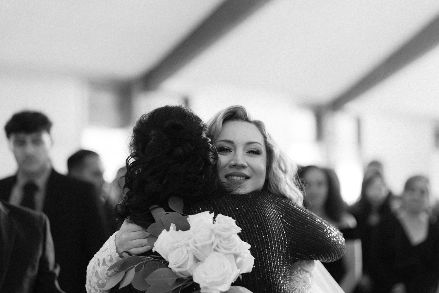 Joyful wedding celebration with guests smiling and embracing.