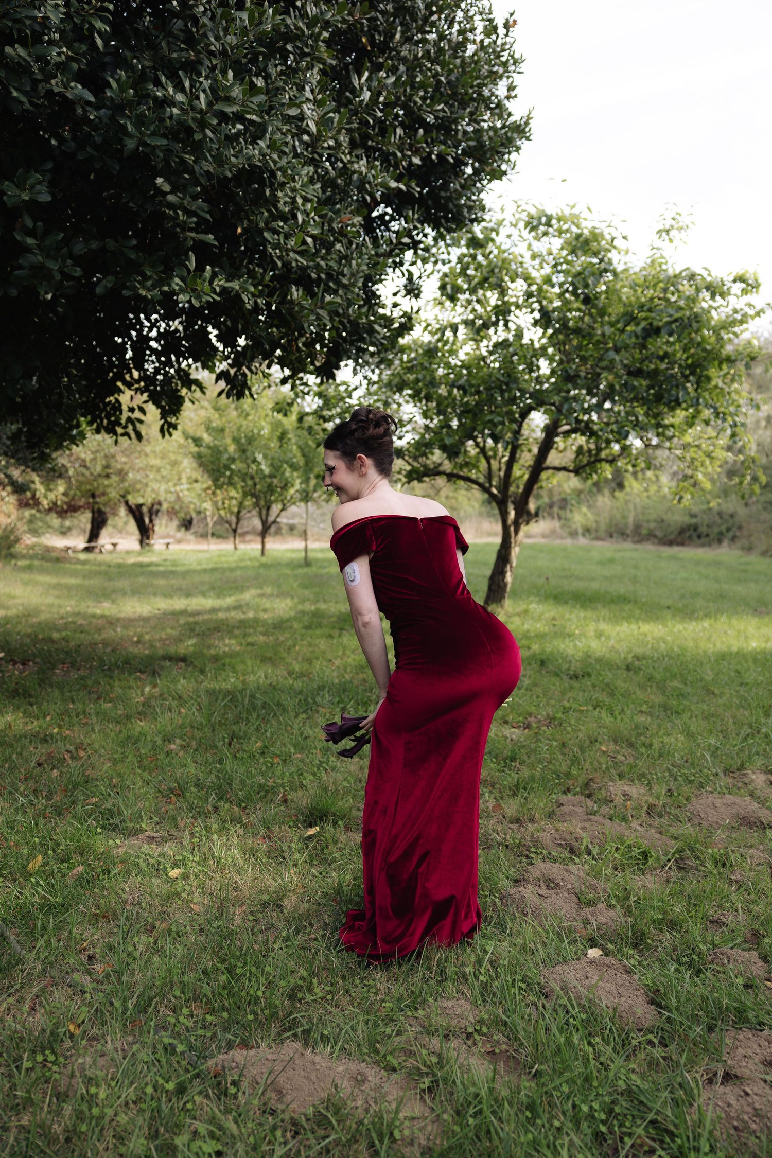 Person in red dress dances and spins through a scenic orchard setting.