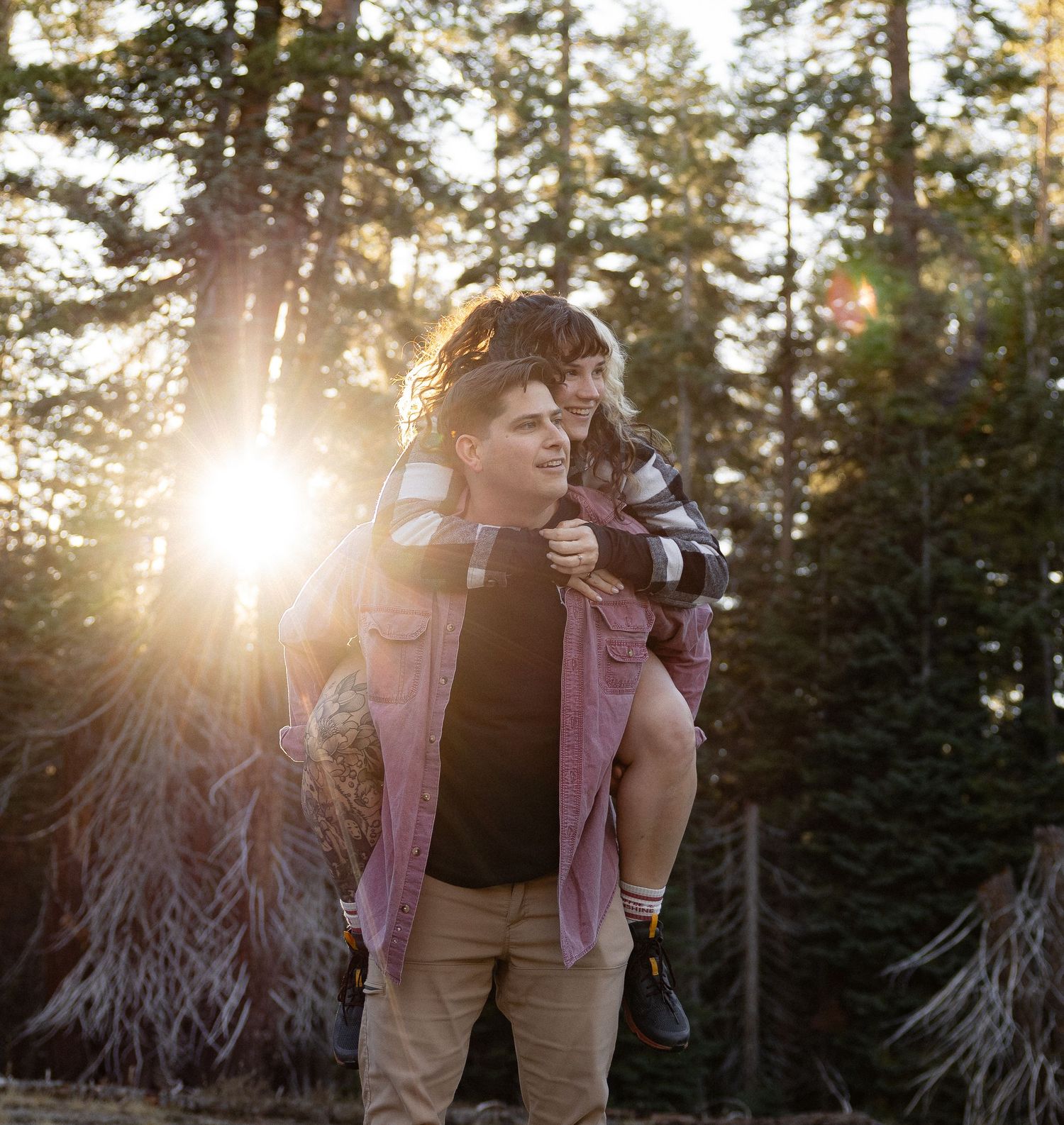 Couple embracing in forest with beautiful sunset light filtering through trees.