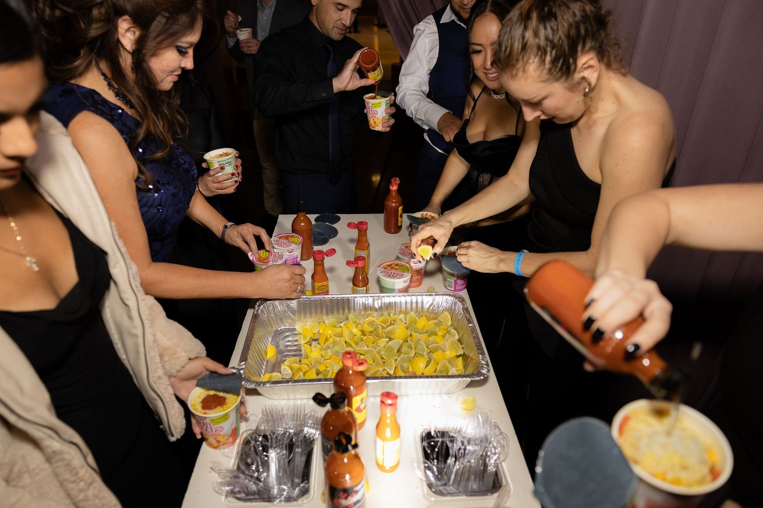 Wedding guests gathered around tables enjoying food and drinks at the reception.