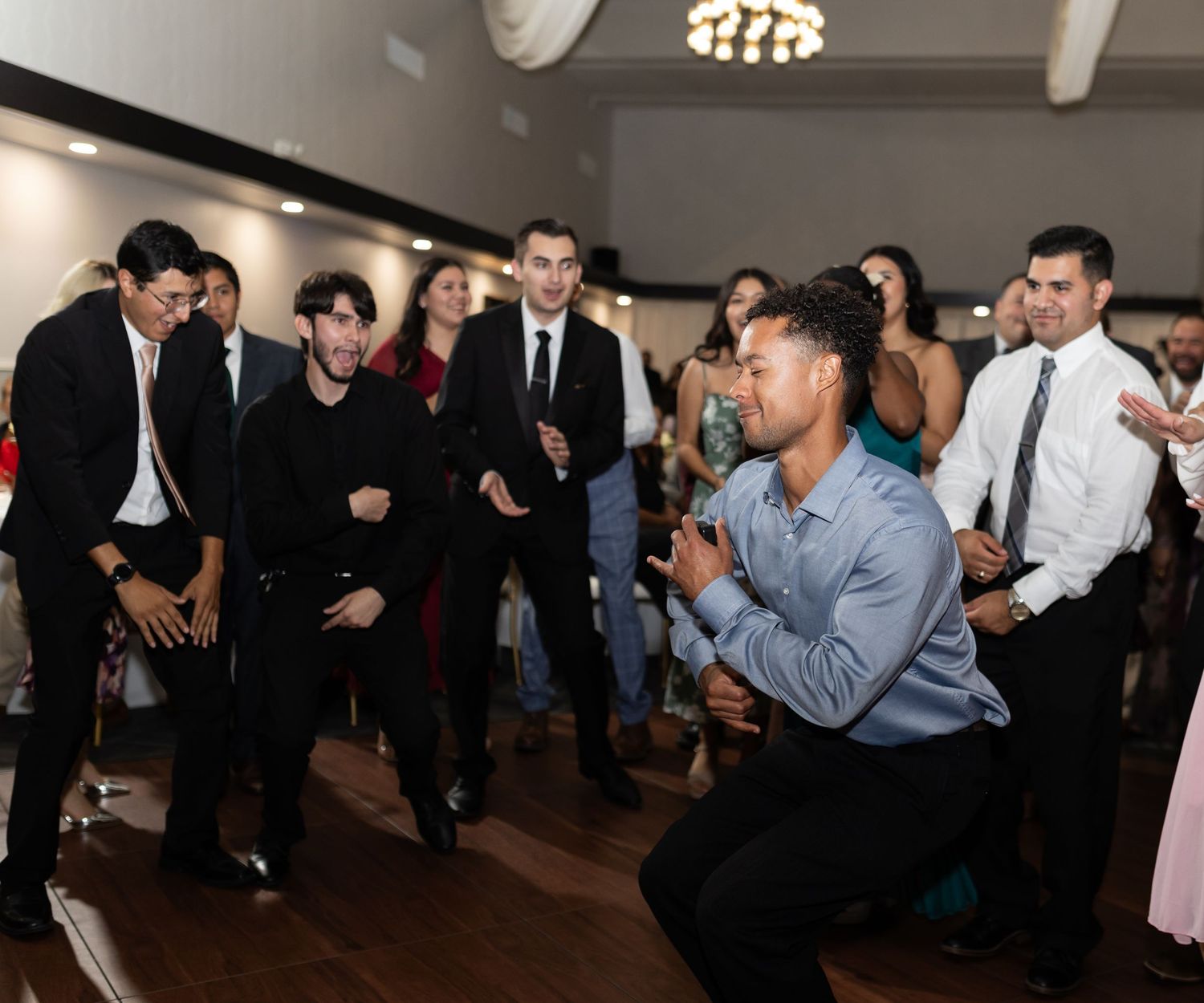 Wedding party guests dancing and having fun on the dance floor during reception celebration.