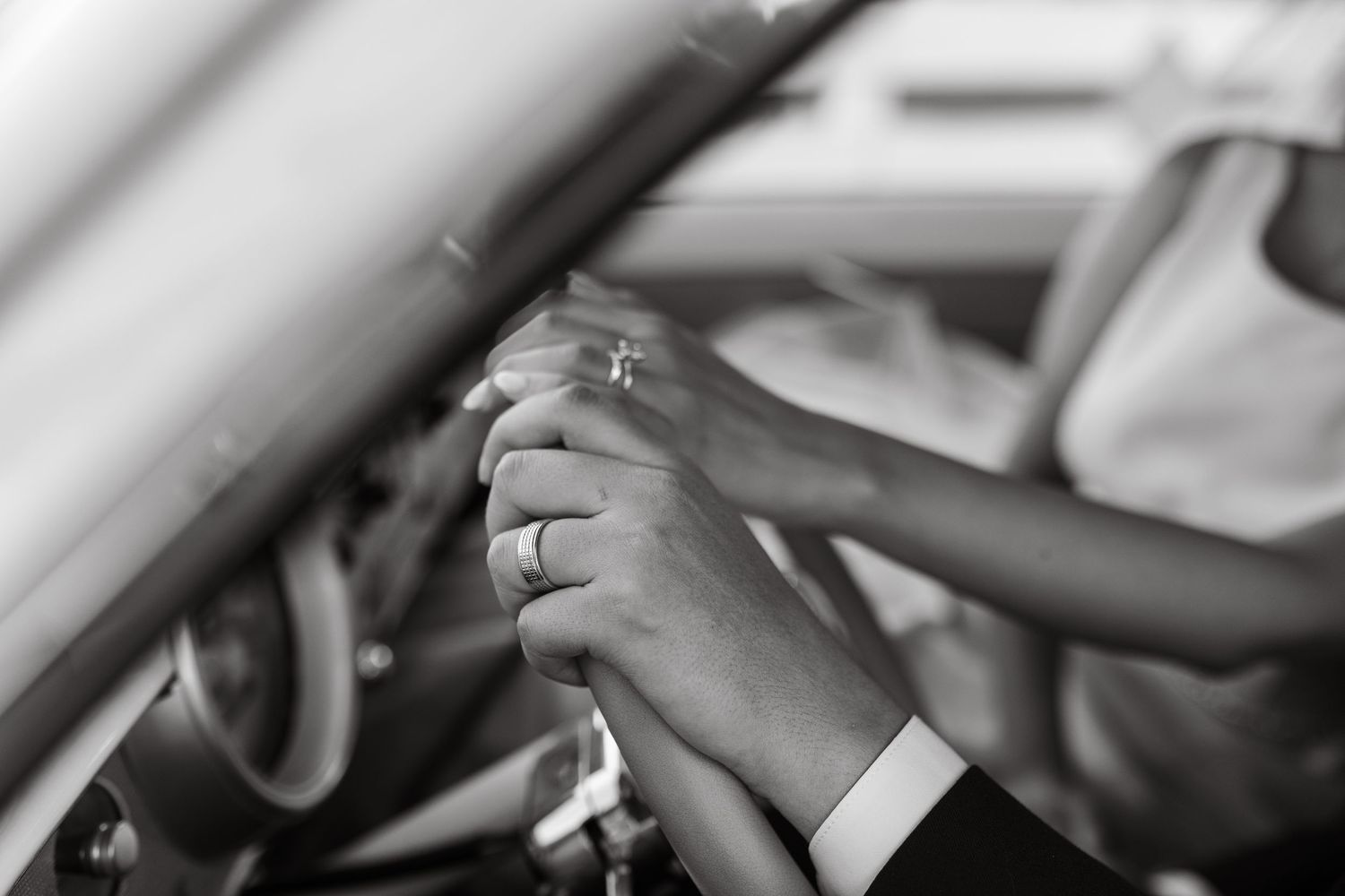 Detail shot of hands gripping a vintage car's steering wheel.