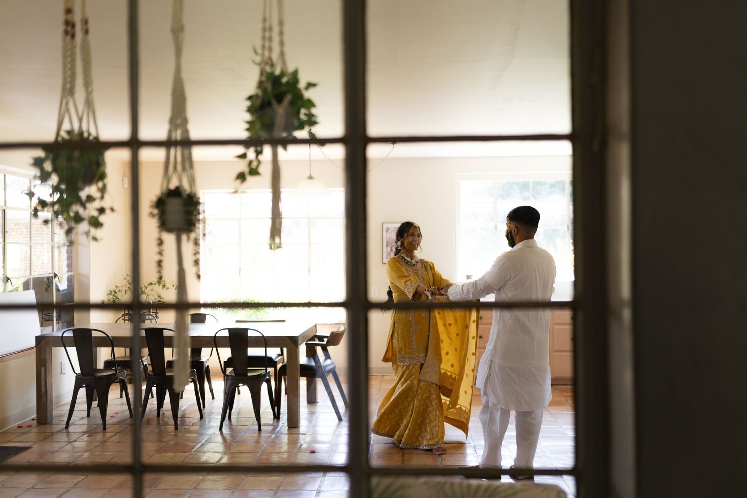 Two people in contrasting white and yellow outfits move through a minimalist interior space with dramatic lighting.