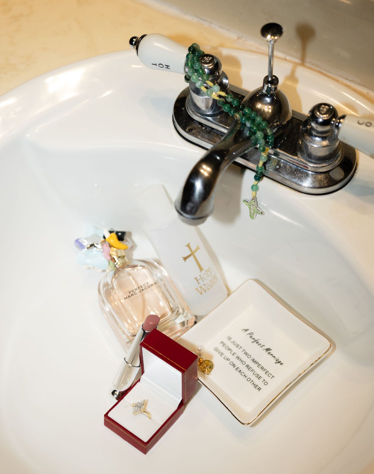 Wedding details including perfume bottles and jewelry displayed on a white surface.