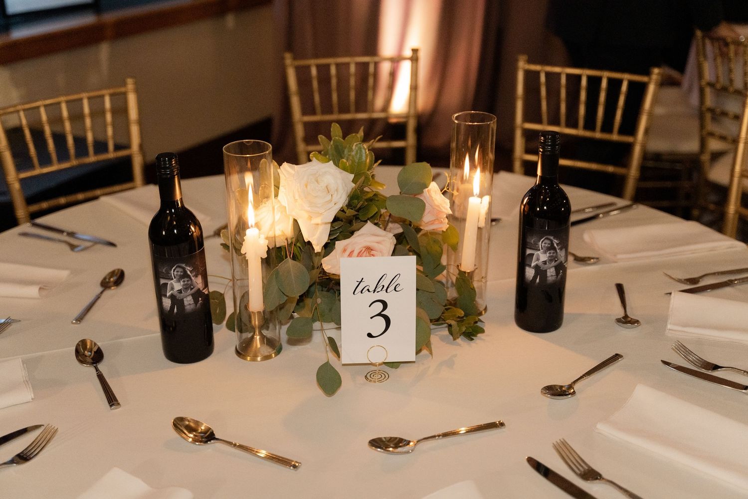 Elegant table settings with candles and greenery at a formal dinner reception.