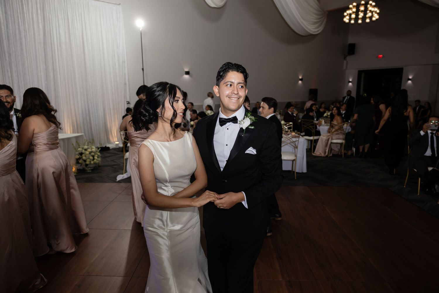 Wedding reception dance floor with couples dancing under elegant chandelier lighting.