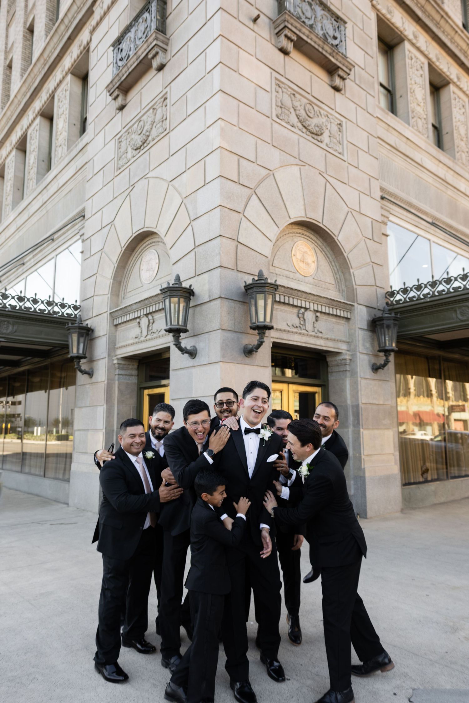 Groomsmen share candid laughing moments during outdoor wedding photography.
