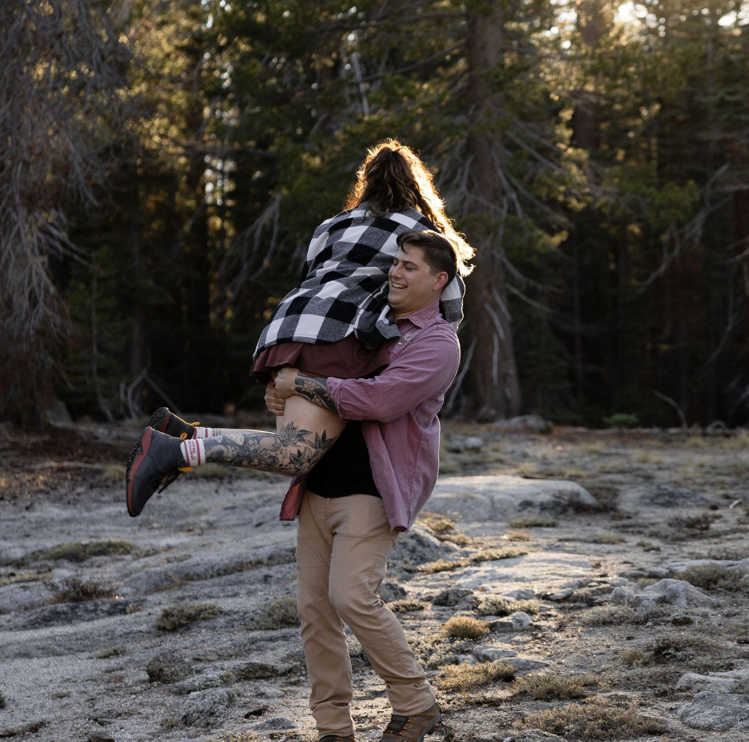 A romantic moment captured between two people on a mountain peak during sunset.