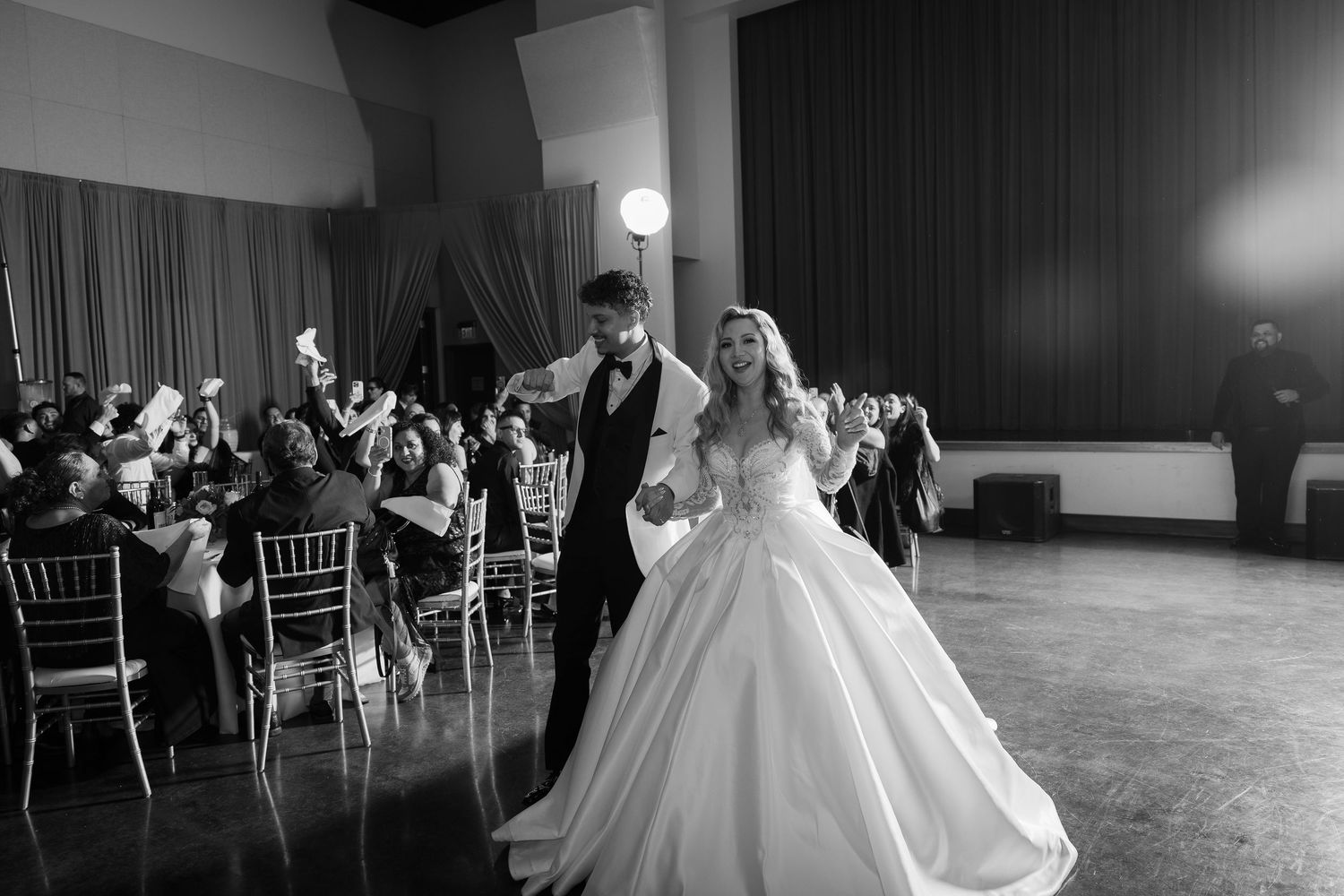 A black and white photo captures a couple's joyful dance moment at their wedding reception.