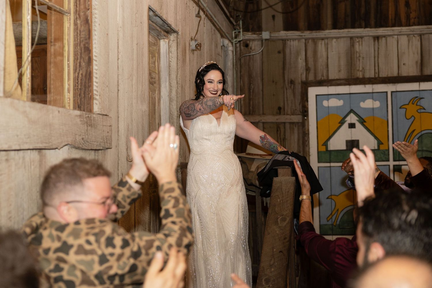 Wedding party dancing enthusiastically in rustic barn venue with wooden walls.