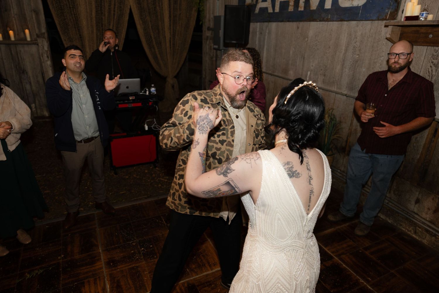 Couples enjoying dance moves at a barn wedding reception with vintage signage in background.