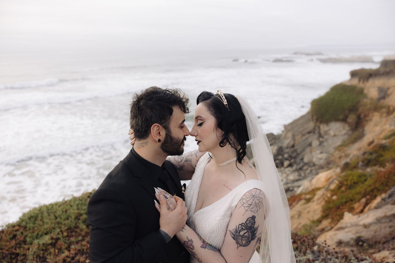 Wedding couple shares a romantic moment on a cloudy day at the California coast.