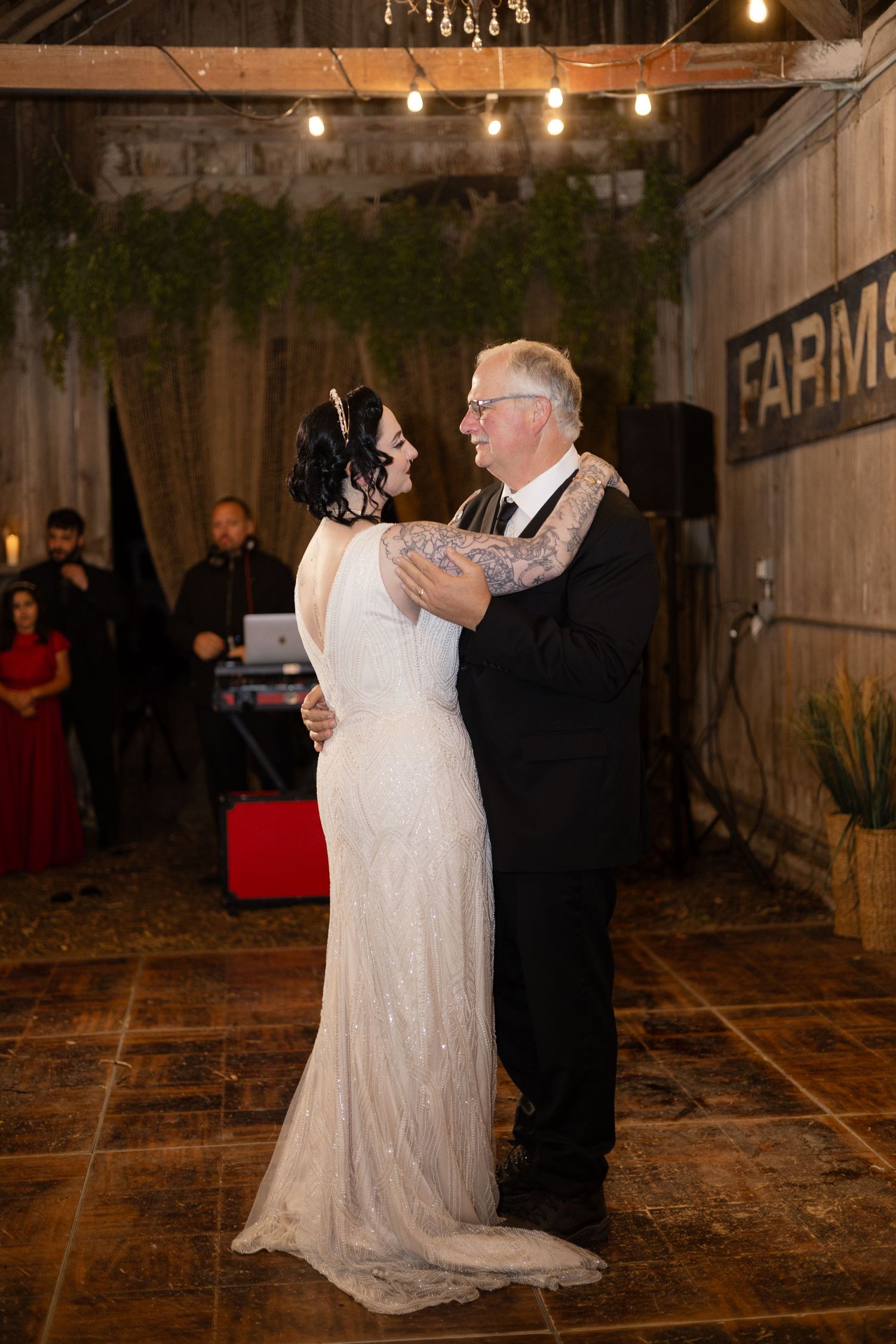 Couple dancing on stone floor under string lights in rustic barn reception venue.
