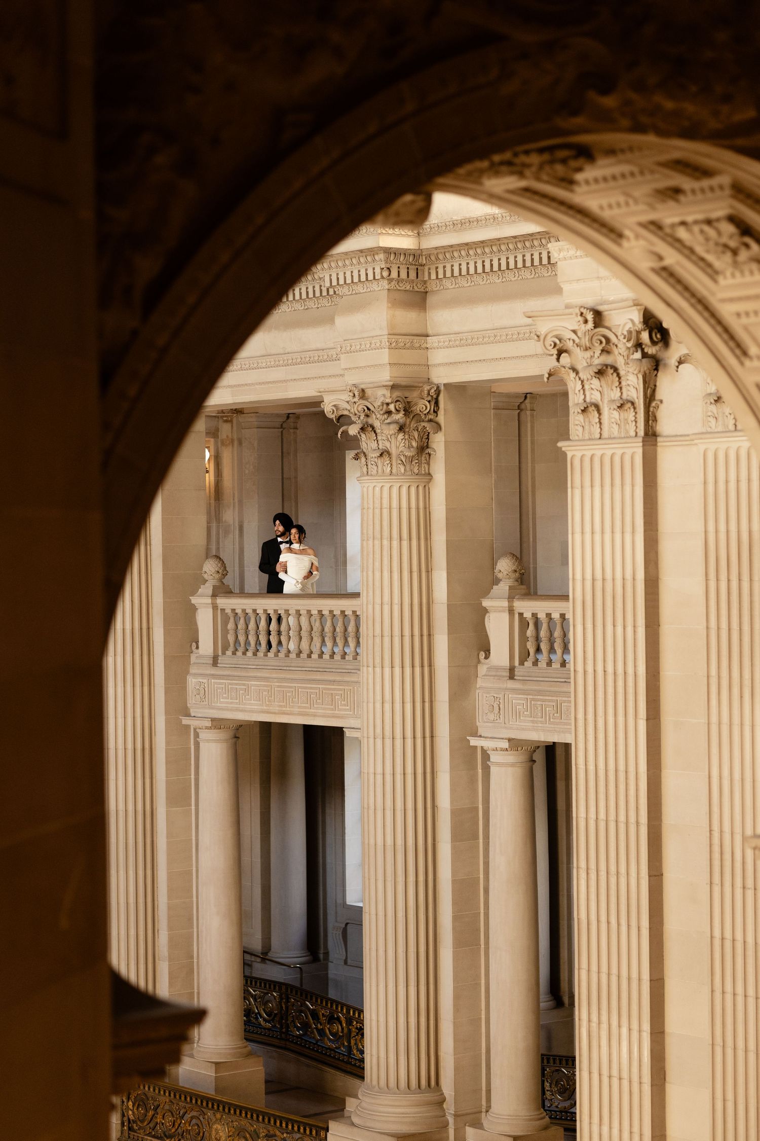 Ornate classical architecture with white columns and balconies viewed through an elegant arched doorway.