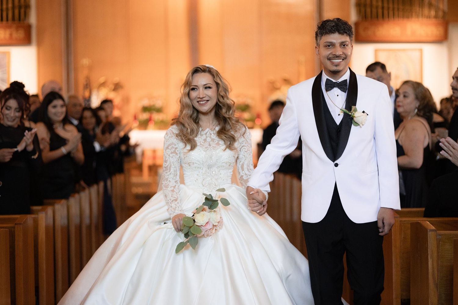 A newlywed couple exits their church ceremony with joyful expressions.