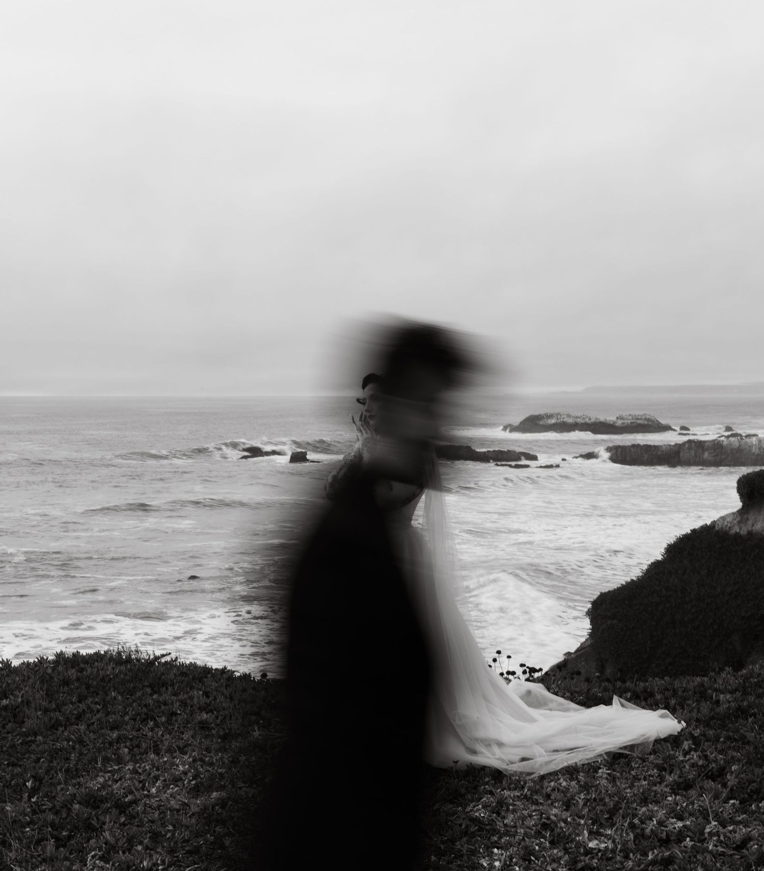 An artistic motion blur portrait creates a ghostly effect against the coastal landscape.