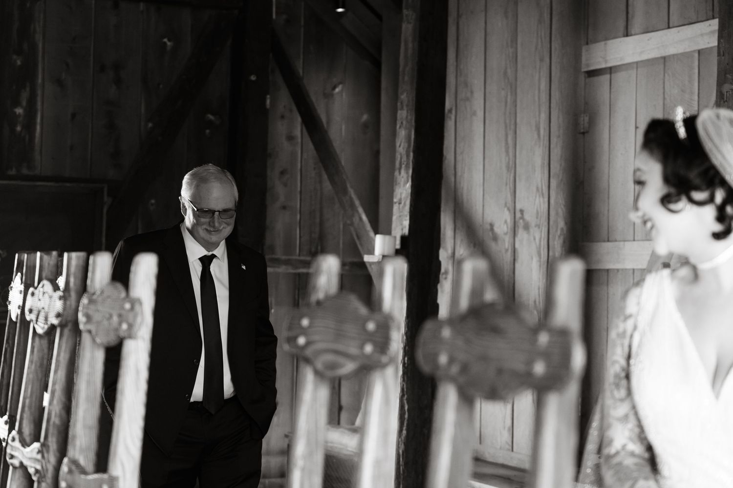 Black and white photo of wedding guests dancing in a rustic barn venue.