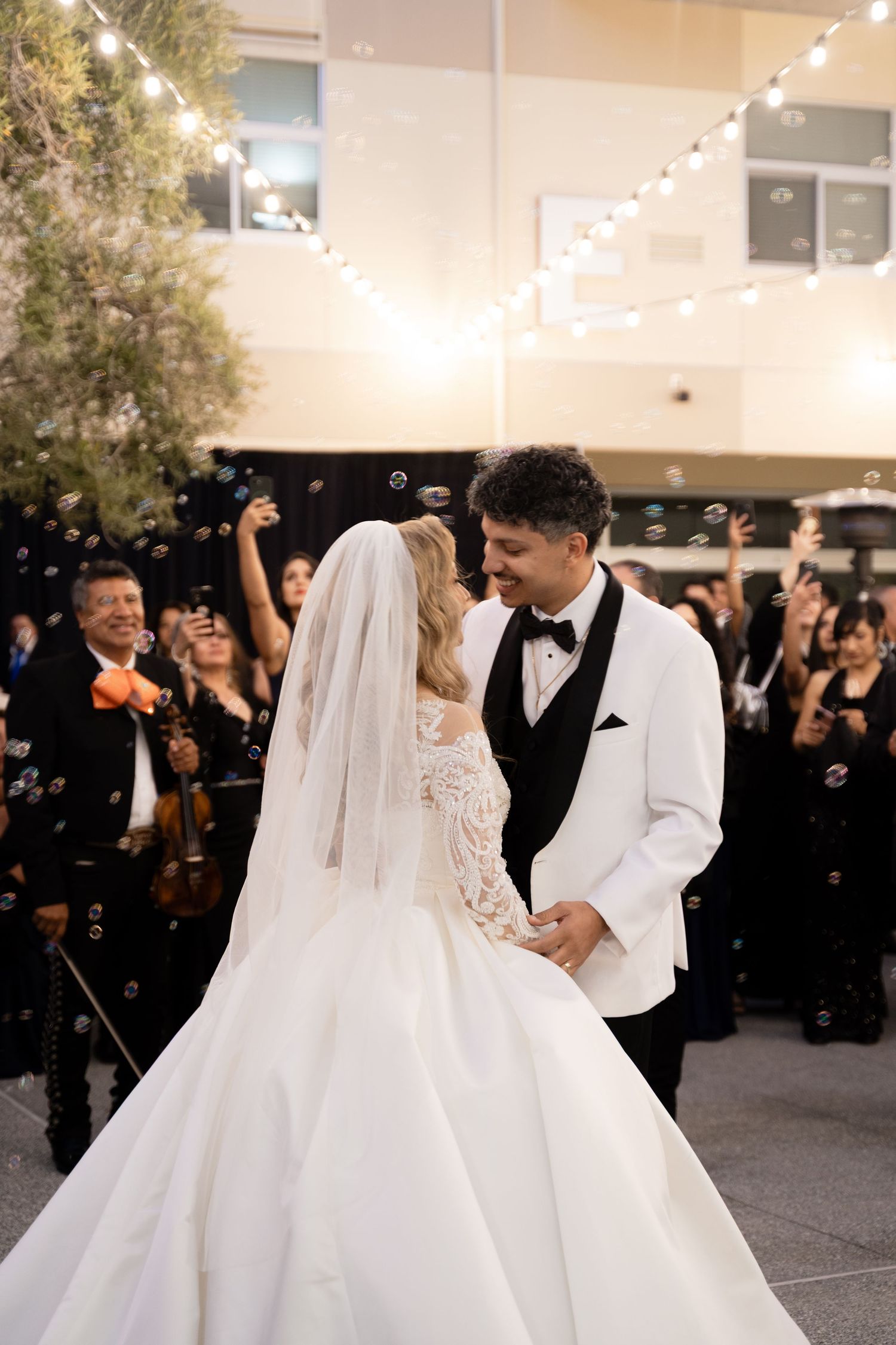 Newlyweds share a romantic dance moment at their wedding reception under twinkling lights.