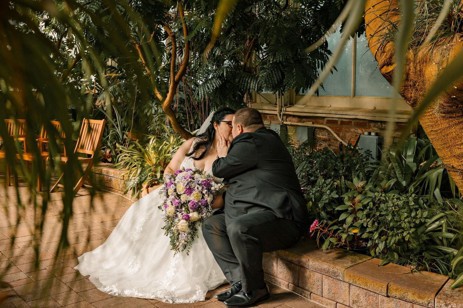 A couple shares an intimate moment in a lush garden setting during their wedding.