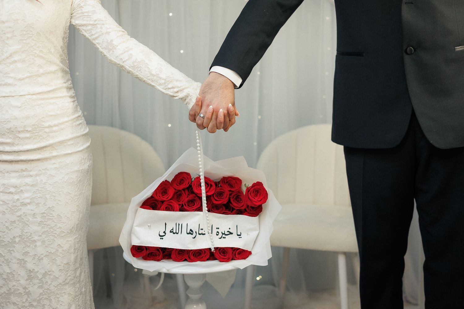 Wedding ceremony setup with white decor and red roses on elegant serving plates.