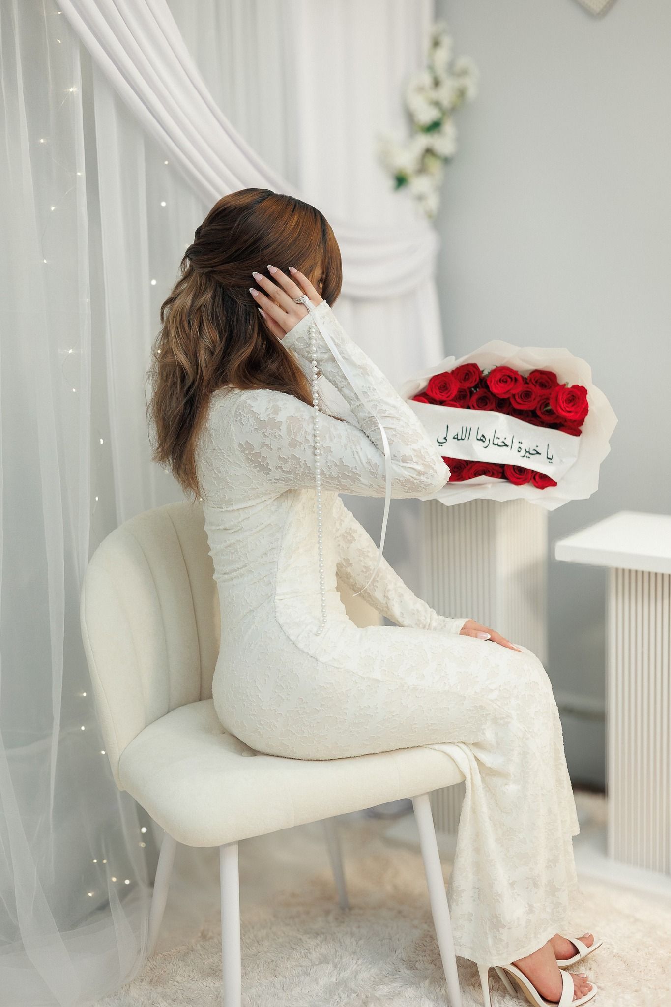 Elegant white room setting with lace details and red rose arrangement on display.