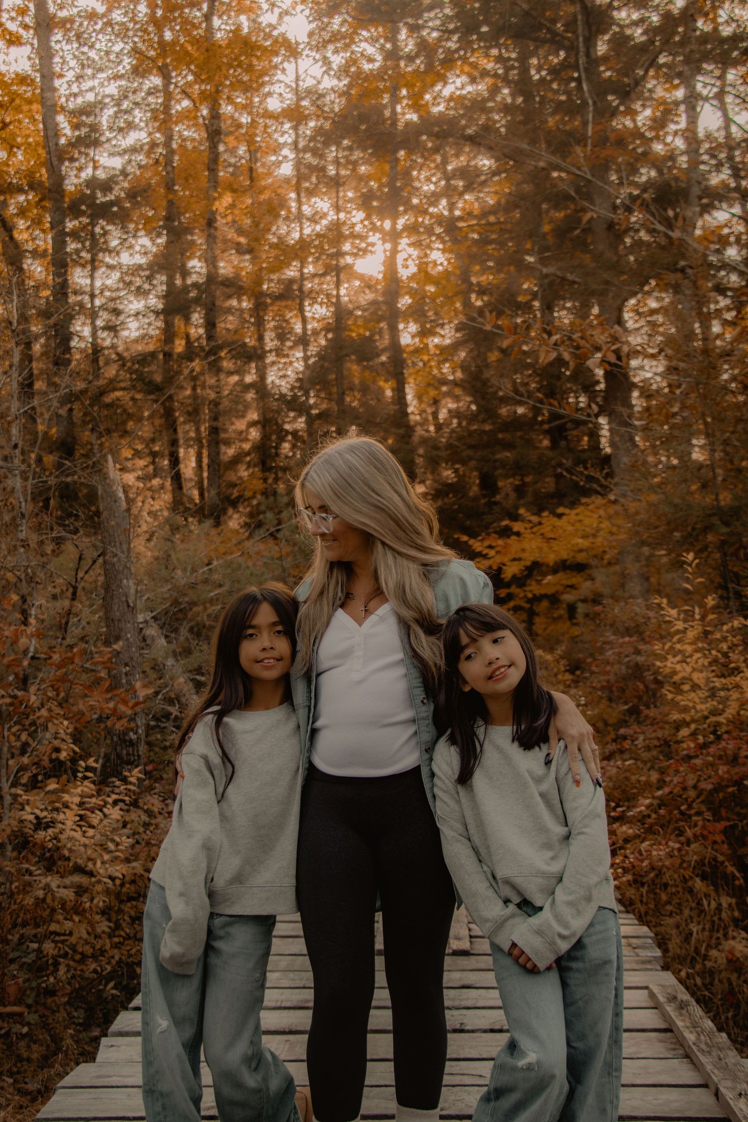 A family portrait on a wooden boardwalk surrounded by autumn foliage.