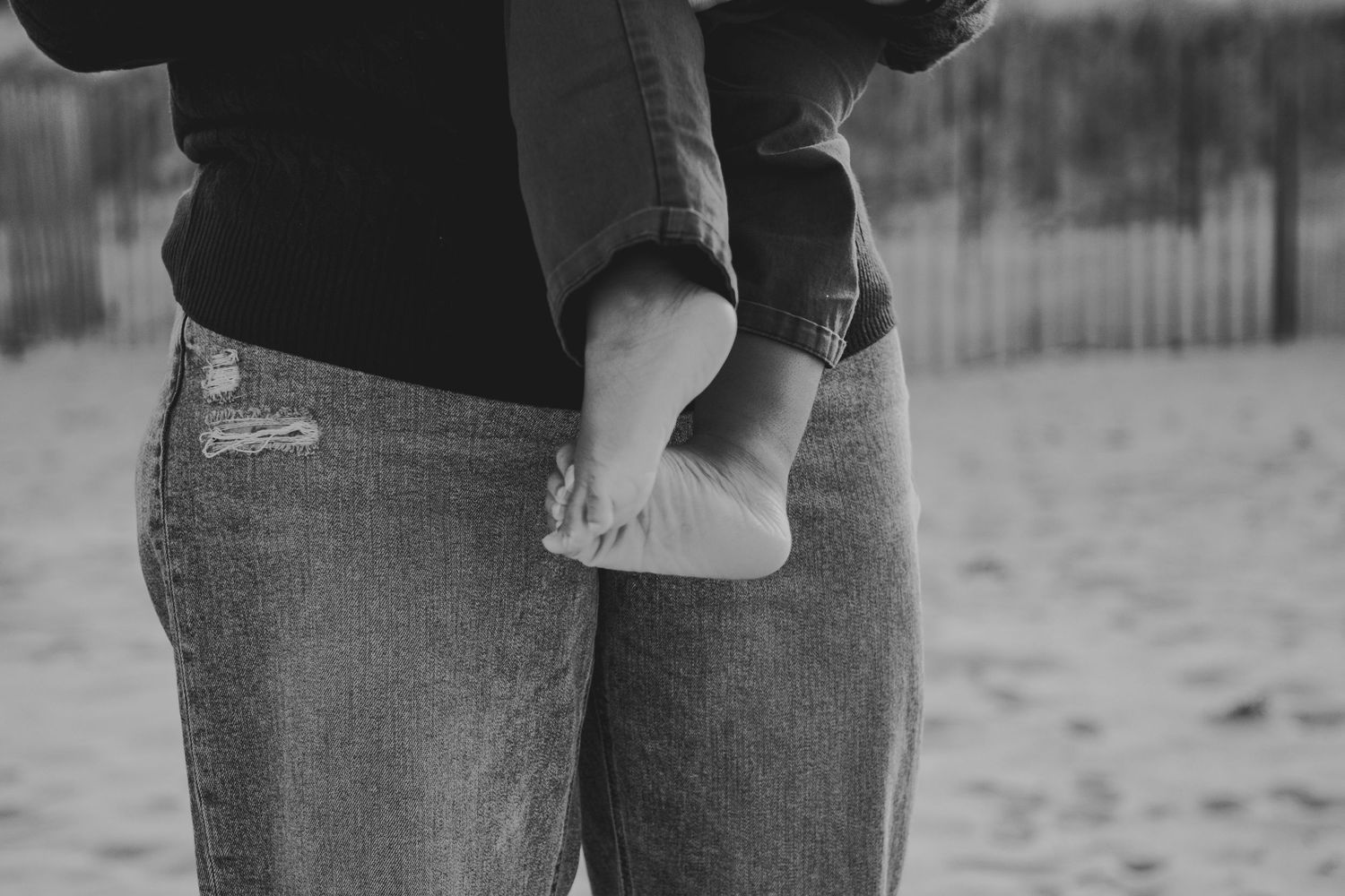 Black and white photo of a couple holding hands while walking together outdoors.