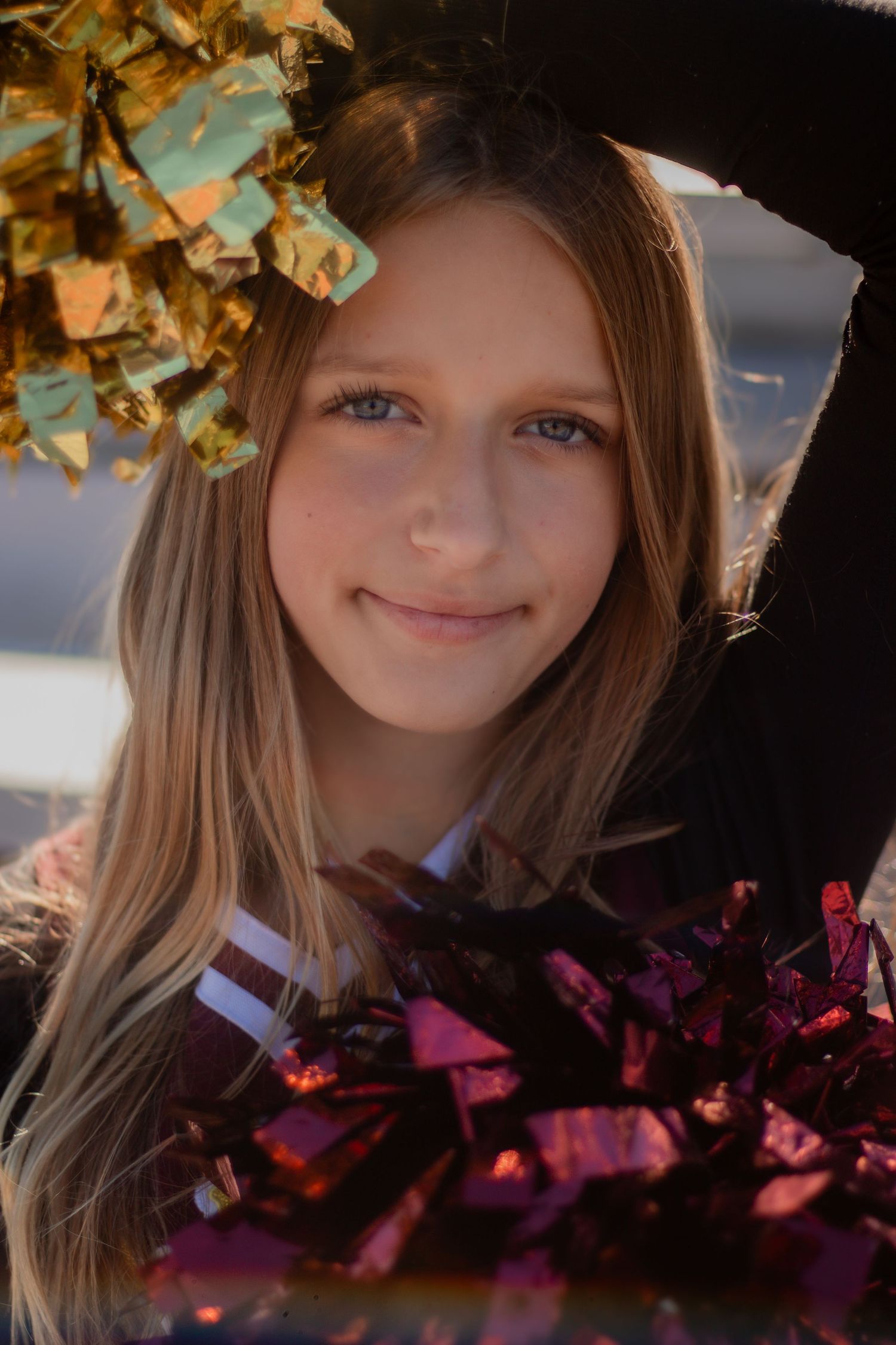 Portrait of a cheerleader with pom poms against an autumn sunset backdrop.