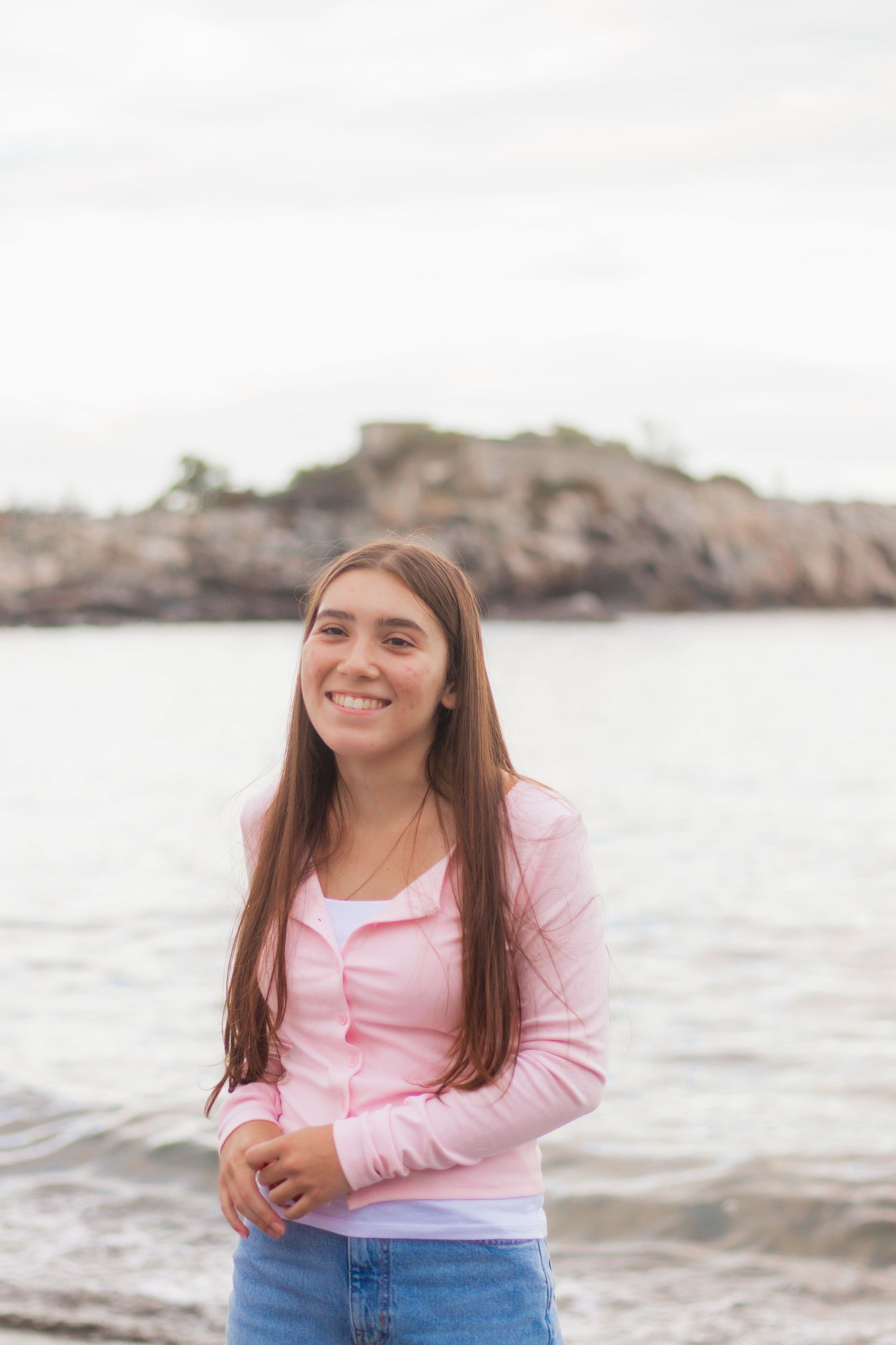 Portrait session by the ocean with rocky coastline in background.