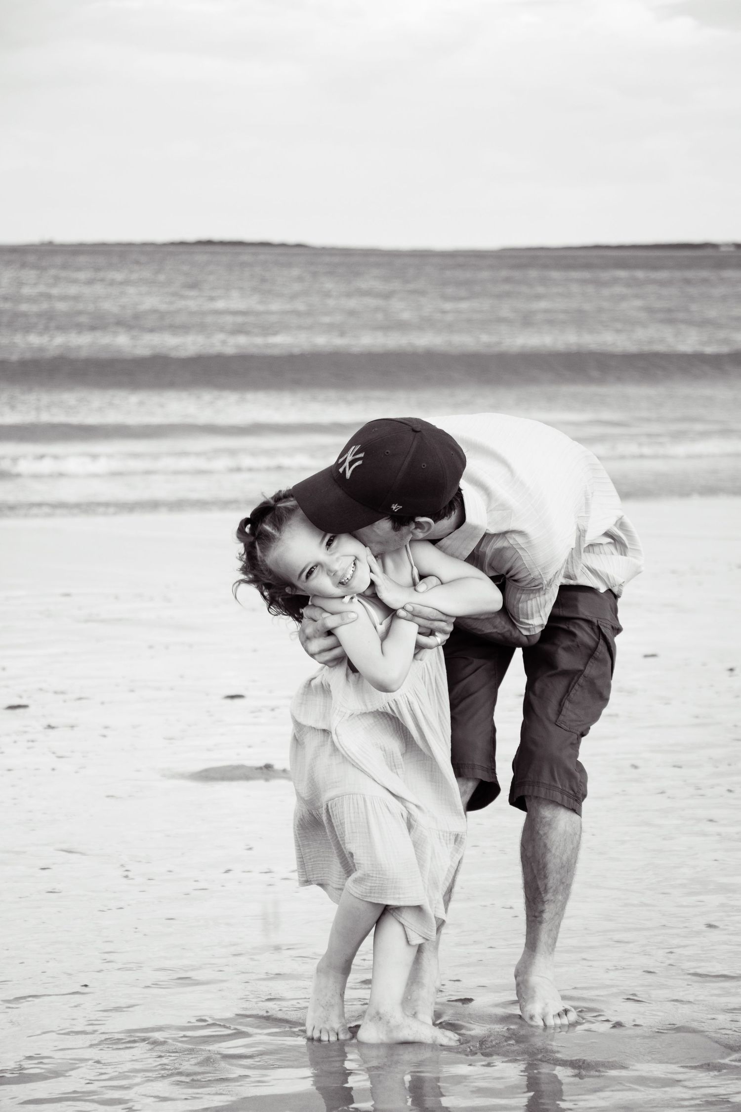 Black and white capture of intimate family moment at the beach.