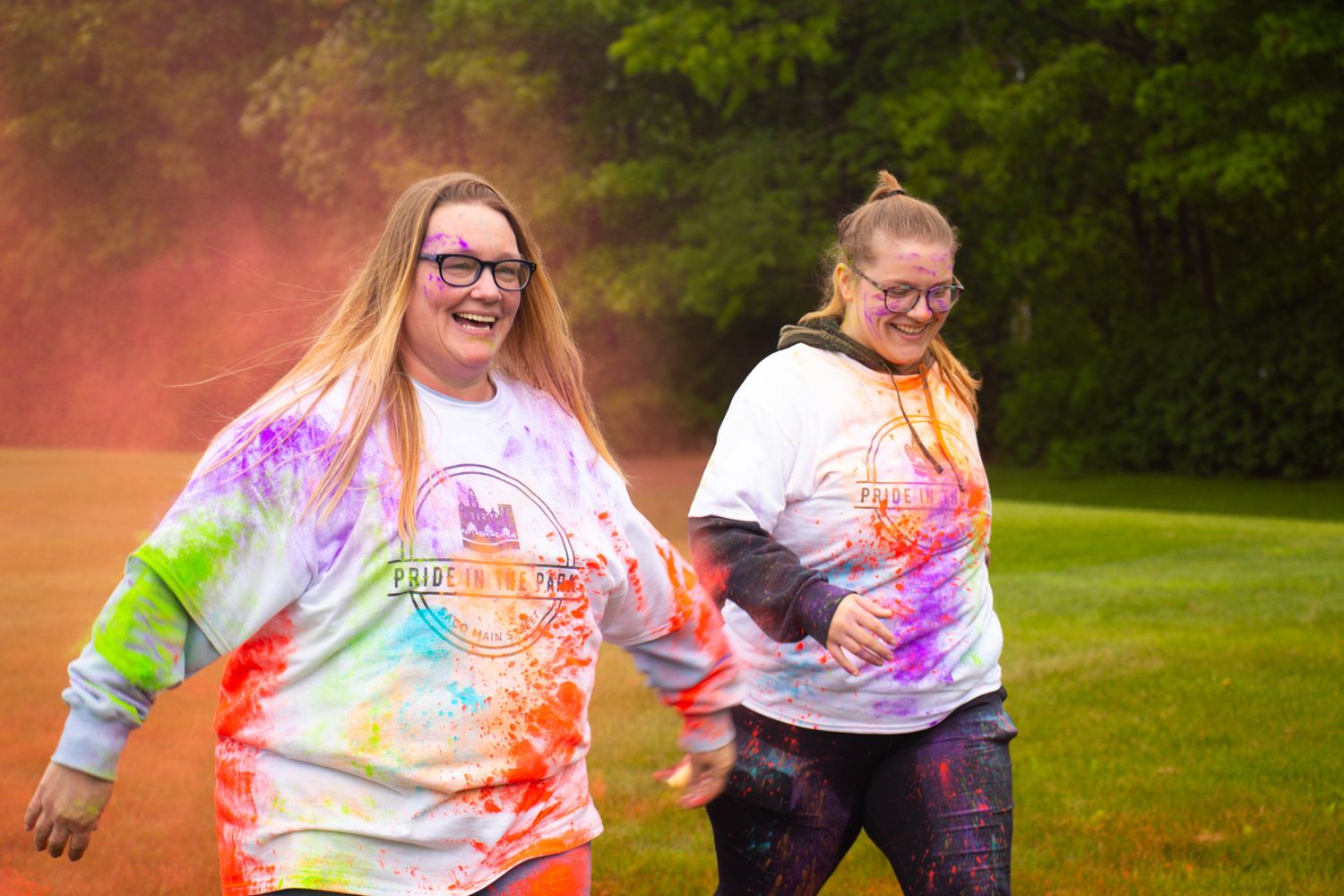 Group wearing tie-dye shirts playing outdoors at sunset.