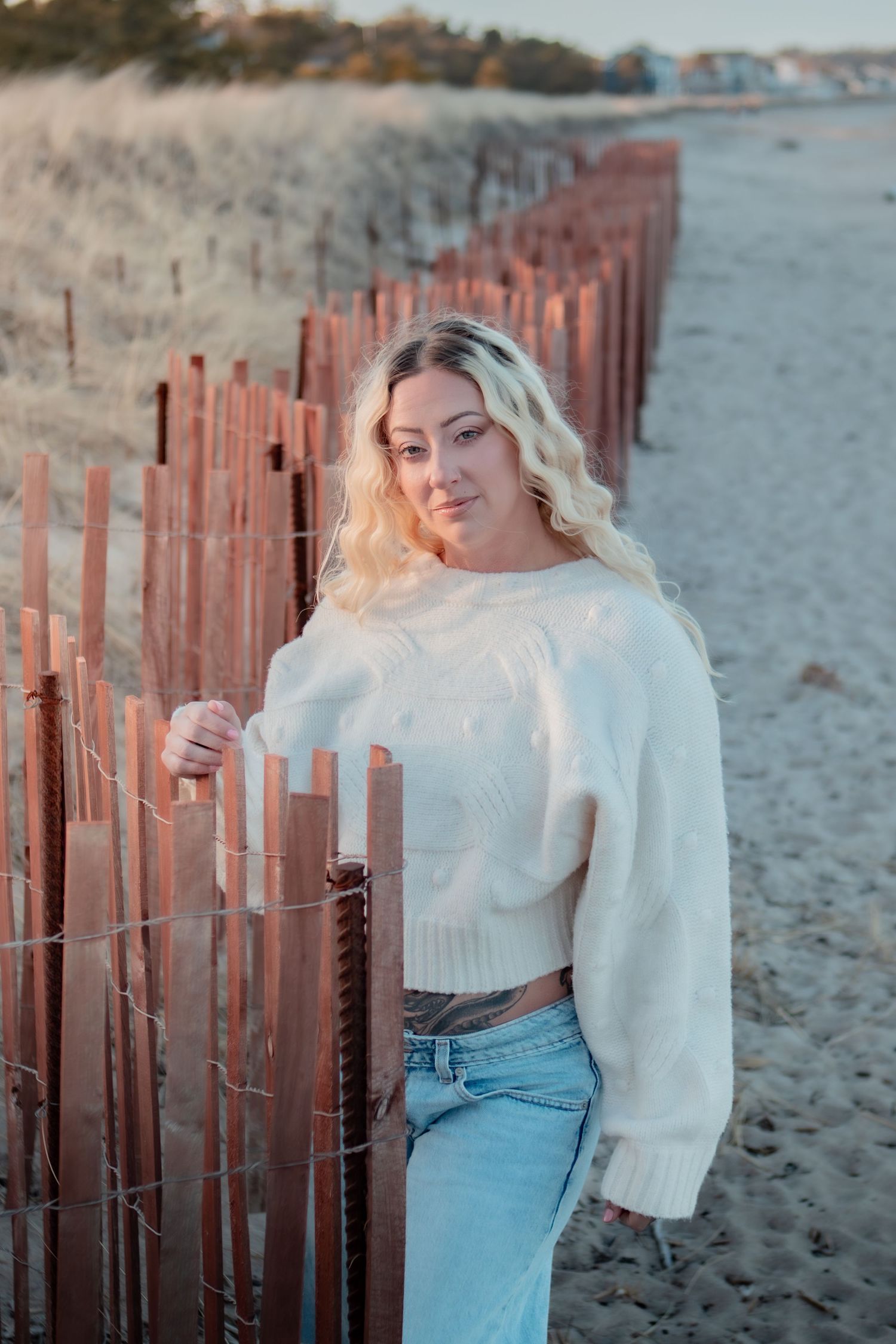 A series of beach photos at sunset featuring a white sweater and jeans against wooden fence posts in the sand.