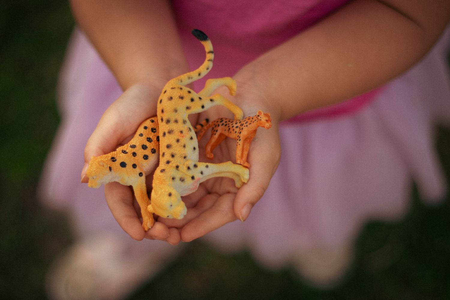 Child's hands holding small toy giraffe figurine.