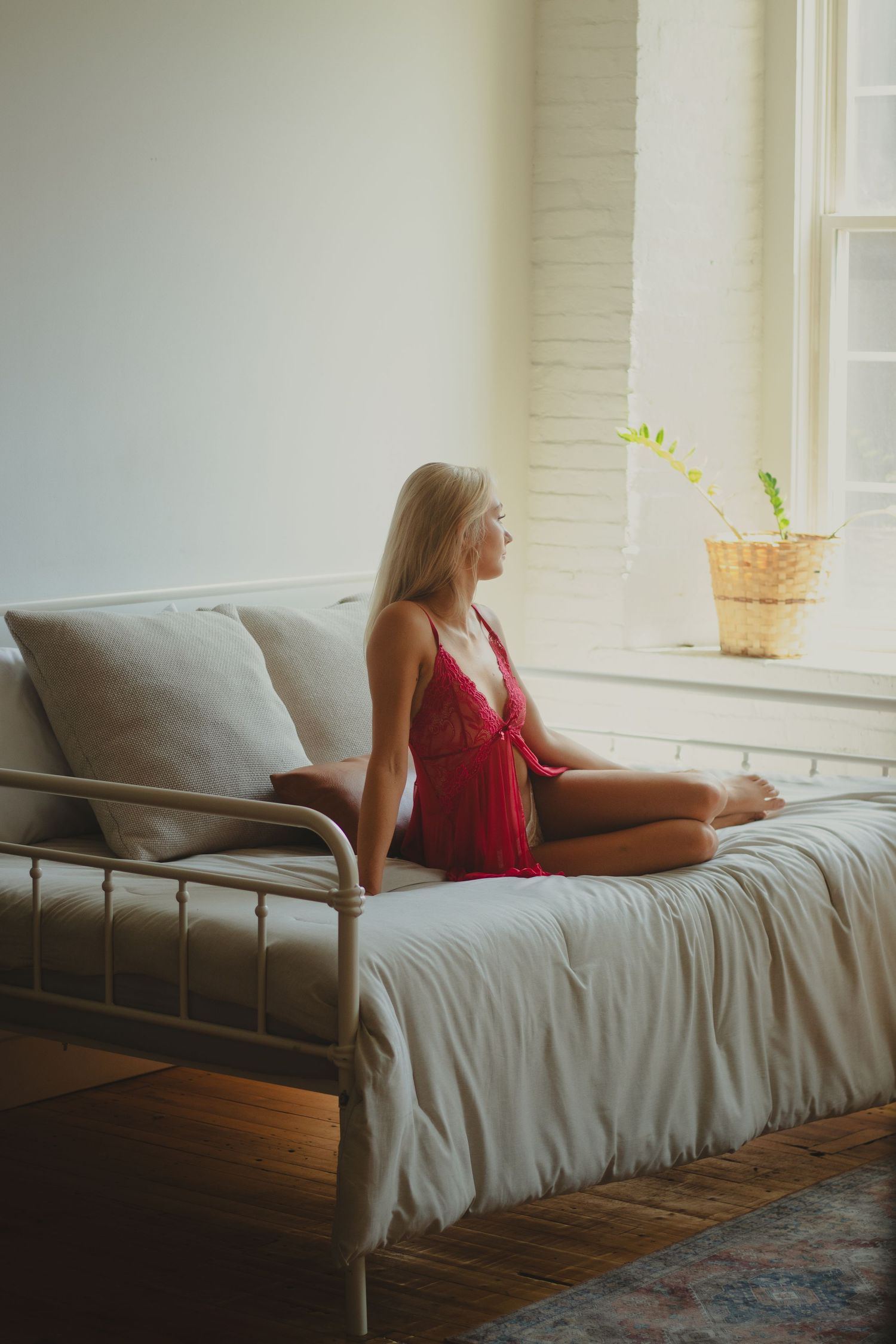 Soft natural light streams through windows onto a gray couch in a minimalist white room.
