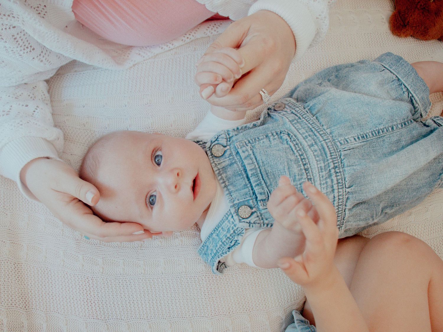 Gentle newborn photography session with soft lighting and denim clothing details.